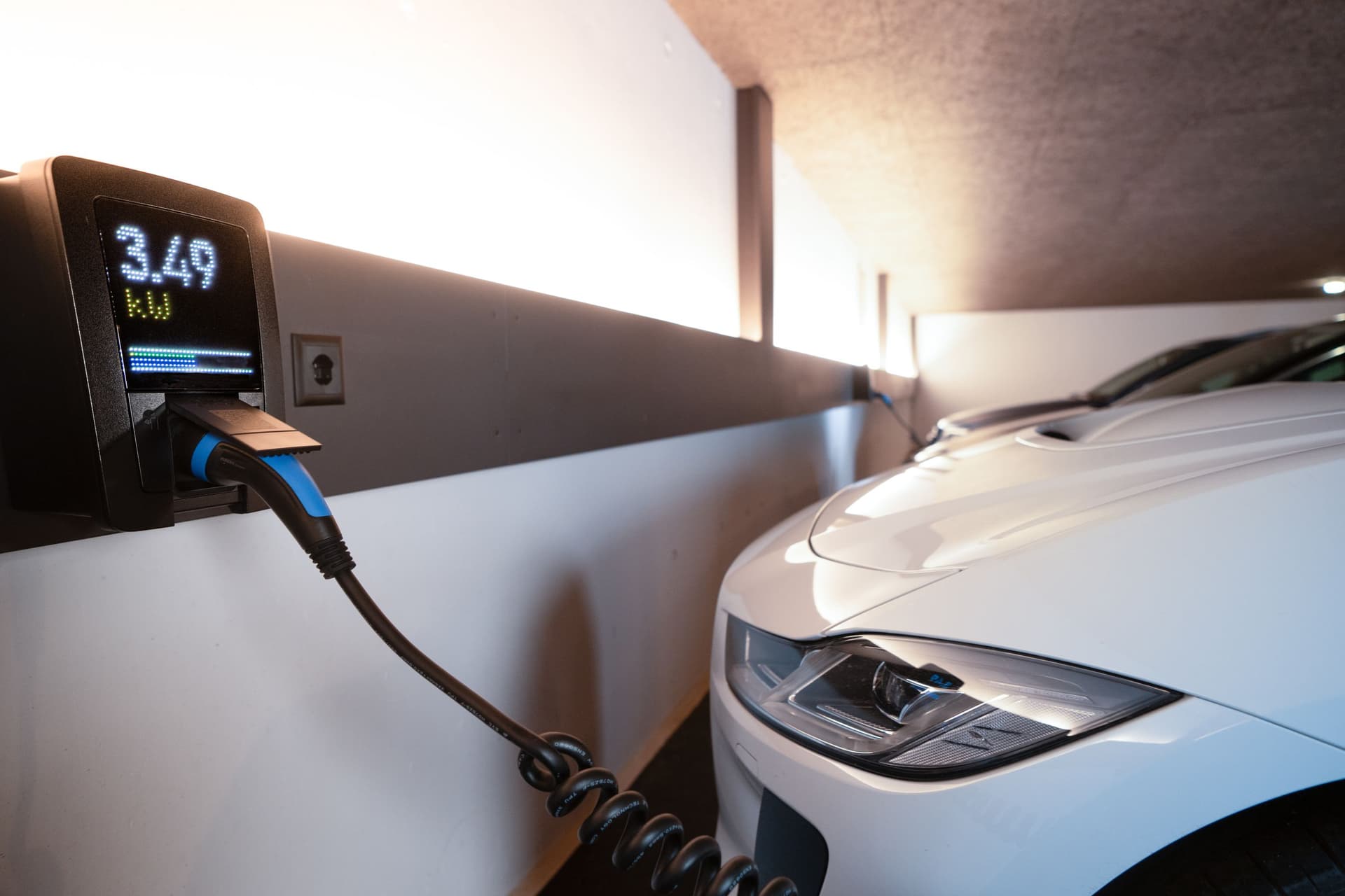 Coche eléctrico blanco cargando en una estación interior de un garaje